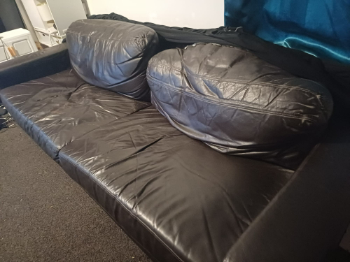 Black leather couch with rounded cushions.