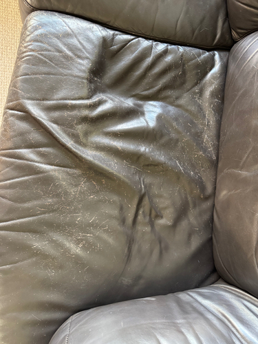 Worn black leather sofa seat with visible creases and scratches.
