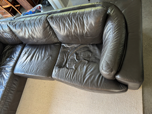 Leather sectional sofa with worn cushions.