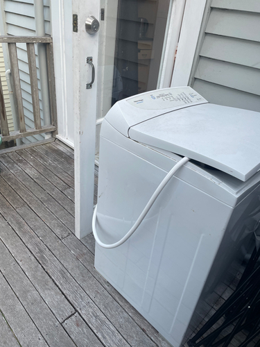 Washing machine with closed lid and hose.connector.