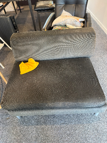 Gray upholstered chair with a yellow cloth on the seat.