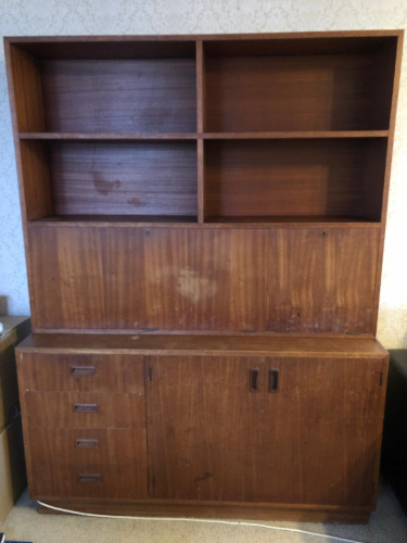 Wooden shelving unit with top open shelves and bottom storage cabinet featuring four drawers.