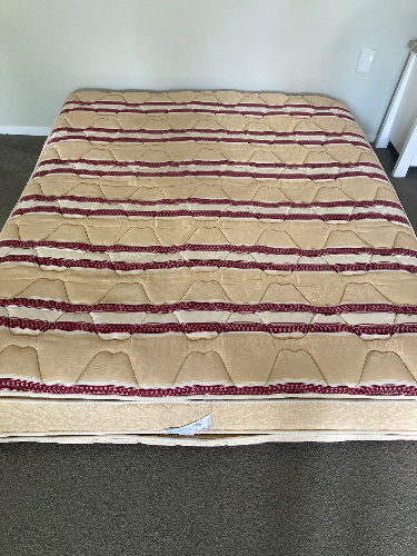 A beige mattress with a striped pattern of red and brown.