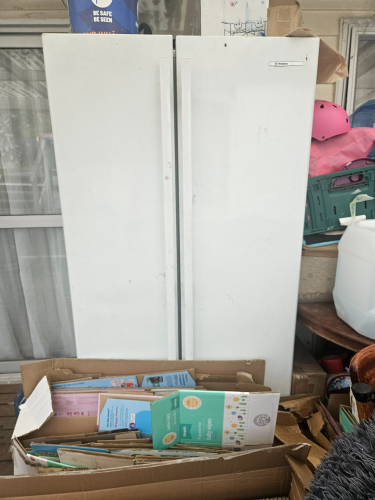 White refrigerator and cardboard boxes with various contents.