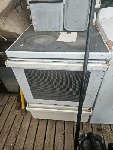 Old white stove with a dirty cooktop and oven door.