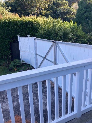 White fence with a gate and a wooden railing.