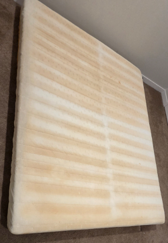 A flat, beige mattress with horizontal ridges.