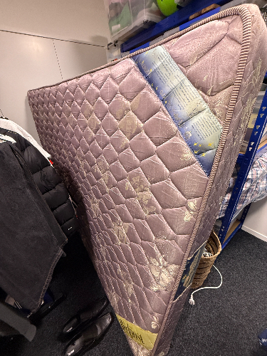 Purple mattress leaning against a wall.