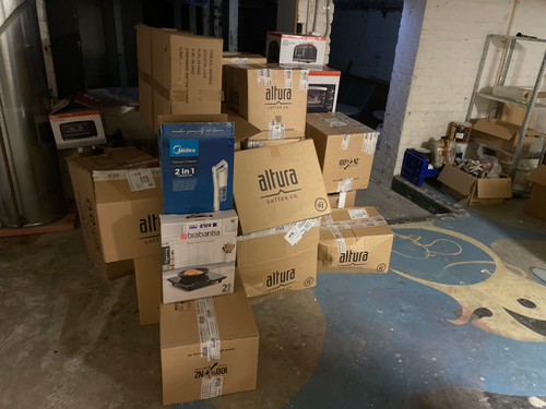 Stacks of cardboard boxes with Altura branding, a box for a 2-in-1 kitchen appliance, and a box for a cooking device.