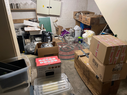 Boxes, storage containers, kitchen appliances, stacked cardboard boxes, and a rug.