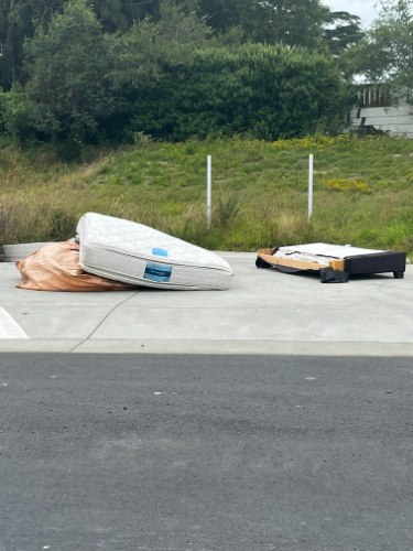Two discarded mattresses, one partially covered with a tarp.