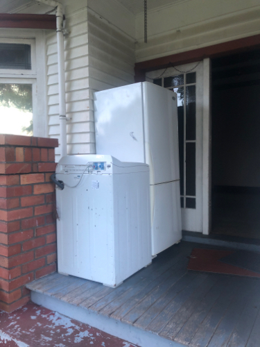 White refrigerator and washing machine on a porch.