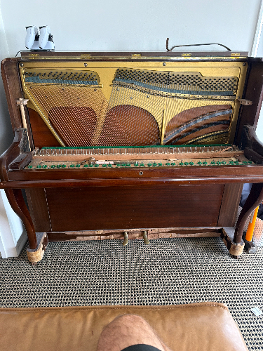 Upright piano with exposed strings and hammers.
