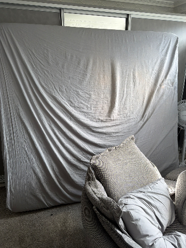 Gray backdrop draped over a surface, plush sofa with pillows.