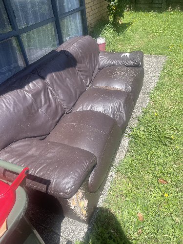 Brown leather couch with visible wear and tear.