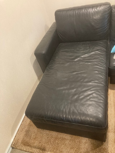 Black leather chaise lounge on a woven rug.