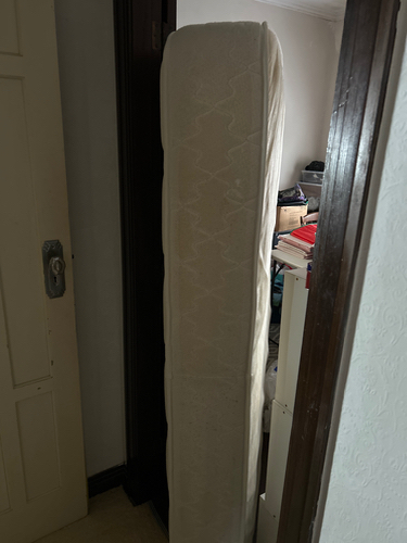 Tall mattress leaning against wall.