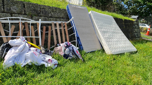 A white mattress, a blue mattress, a bed frame, and assorted bedding.