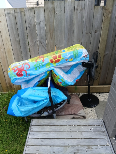 A colorful inflatable pool with a fan and a blue tarp.