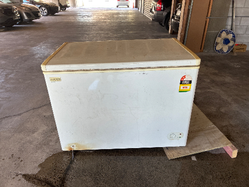 White chest freezer with a yellowed lid and a warning label.