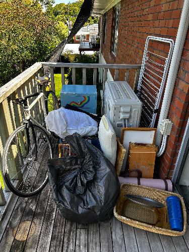 Bicycle, black garbage bag, white pillow, colorful box, white appliance, wooden boxes, roll of fabric, woven basket, blue container, folding drying rack.