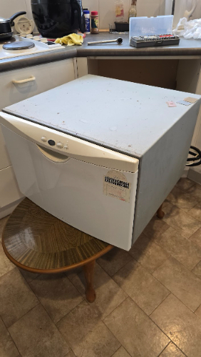 A white chest freezer on a wooden stool.