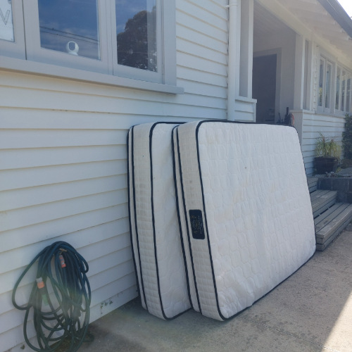 Two stacked mattresses and a coil of garden hose.