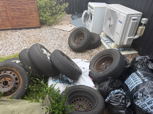 Piled tires, air conditioning unit, garbage bags.
