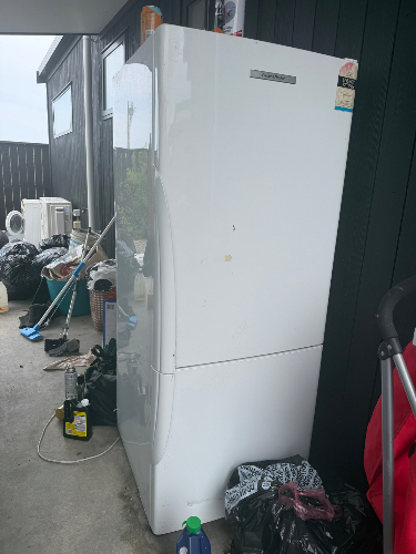 White refrigerator, cleaning supplies, garbage bags.