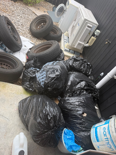 Black garbage bags, old tires, air conditioning unit, blue bucket, white container.