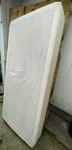 White mattress leaning against a wall.