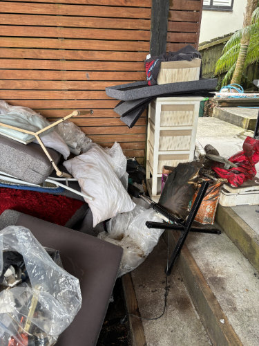 Pile of discarded furniture, including a chair, cushions, and a white storage unit.