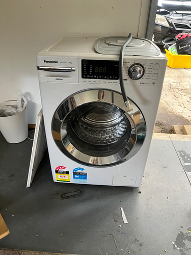 White Panasonic washing machine with digital display and circular door.