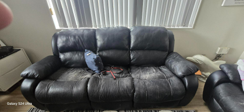 Black leather couch with a blue backpack and red straps.
