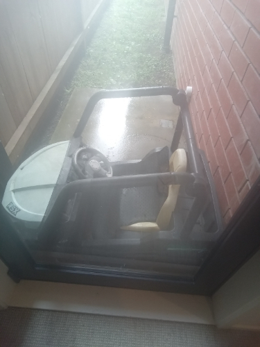 Small toy car with a steering wheel and seat, partially visible through a glass door.