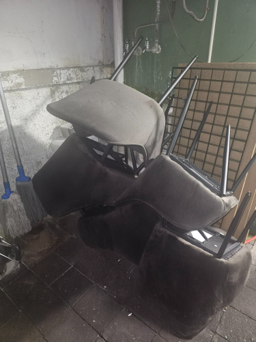 Stacked gray fabric chairs with metal legs.