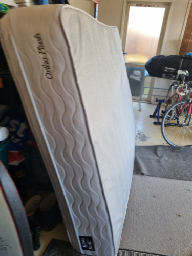 Matress leaning upright with a label that reads "Ortho Plush."