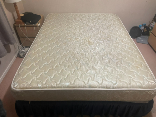 Mattress with a quilted pattern and a black bed skirt.