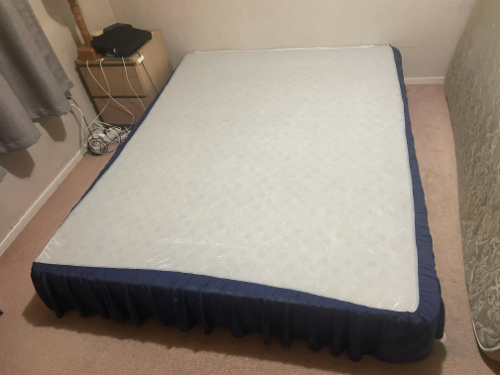 A bed mattress with a blue skirt.