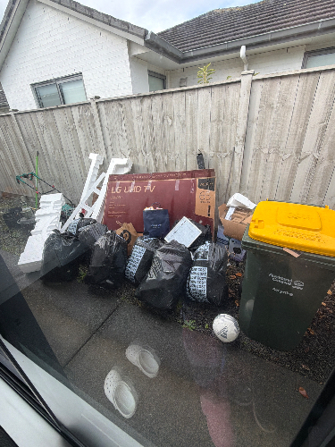 Black garbage bags, a box for an LG UHD TV, a yellow waste bin, a green recycling bin, a white soccer ball, and items including pieces of plastic and cardboard.