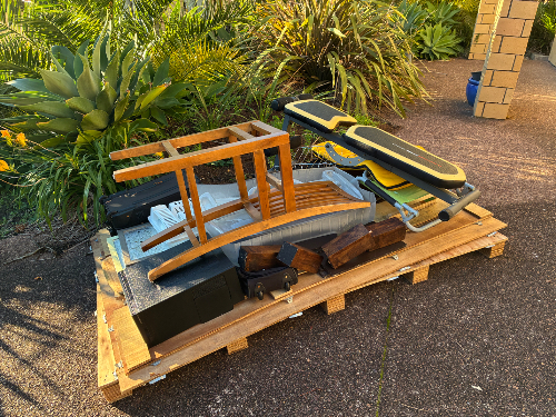 Wooden stool, ironing board, metal basket, wooden planks, black box, yellow and black equipment.