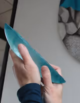 Jo  Richards Hooker's hands close up holding a cast glass turquoise and clear boat vessel