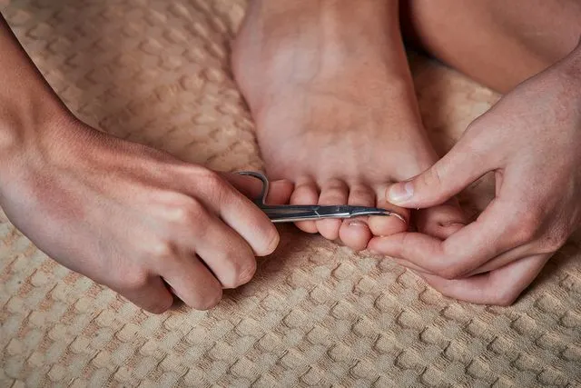 Hands trimming toenails with nail clippers during a pedicure.