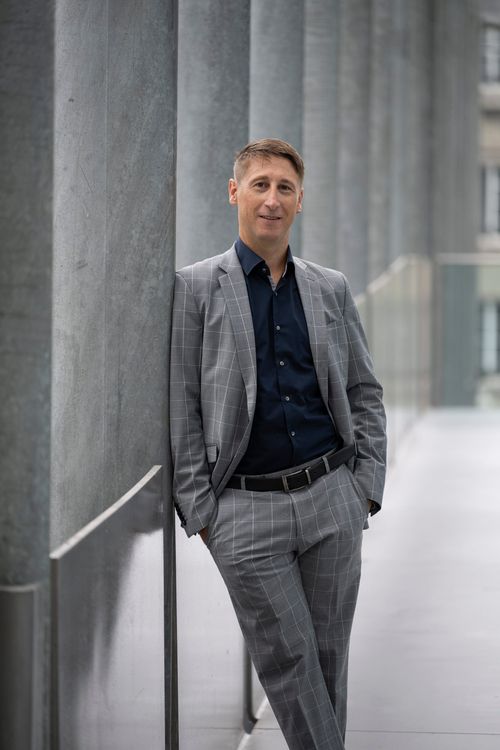 Portrait von Res Ursus Höschele draussen, angelehnt, an einer Säule.