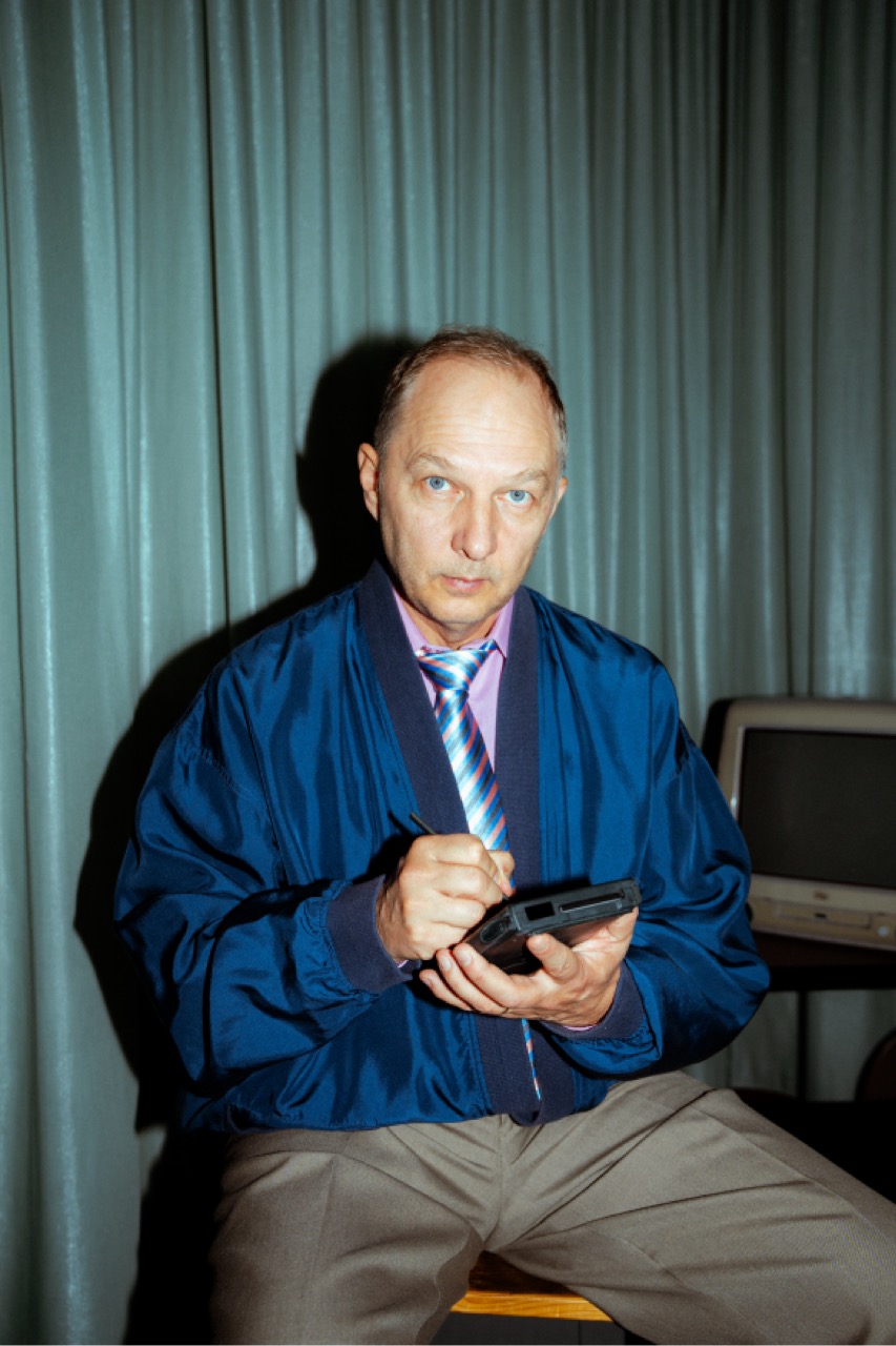 Marius im glänzenden Blazer, schreibt mit einem Stift auf einem alten PDA.