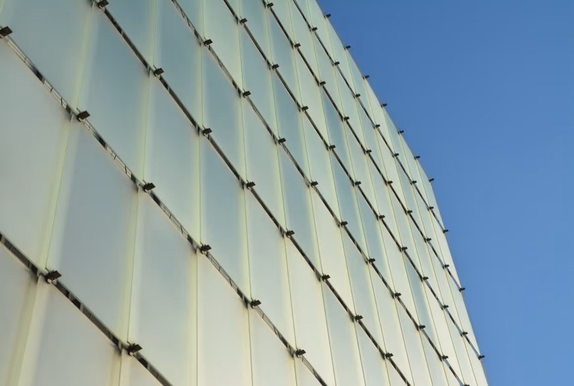 Fassade eines modernen Gebäudes mit lichtdurchlässigen Glaspaneelen im Raster.