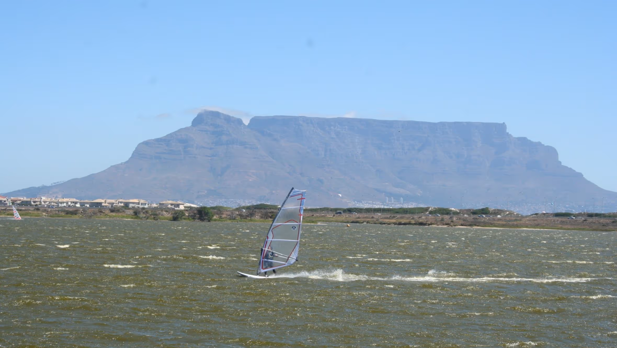 Windsurfer auf dem Wasser vor dem Tafelberg in Kapstadt.