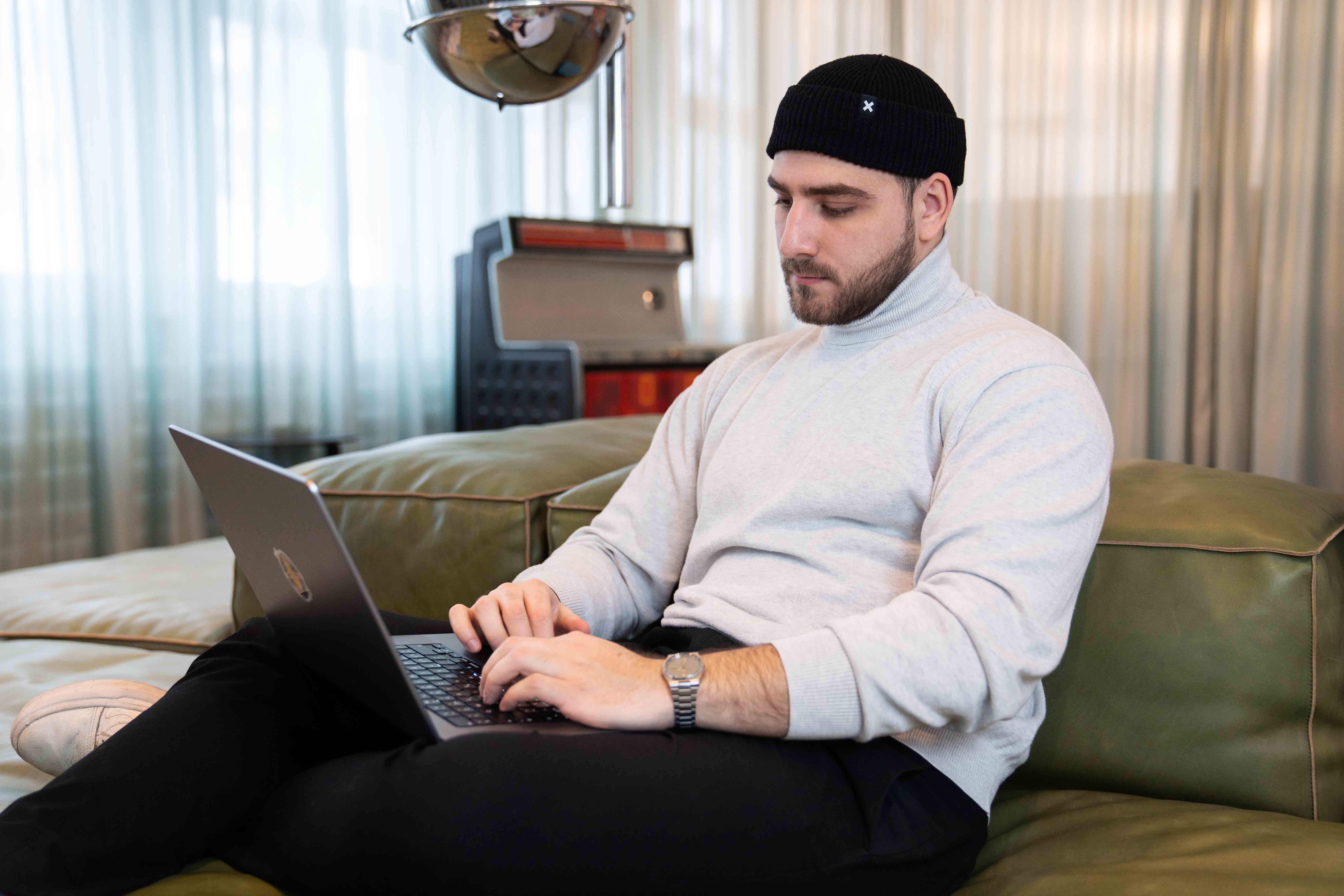 Porträt von Nikita Scherbakov, Code bei Festland, am Laptop auf einem grünen Ledersofa.