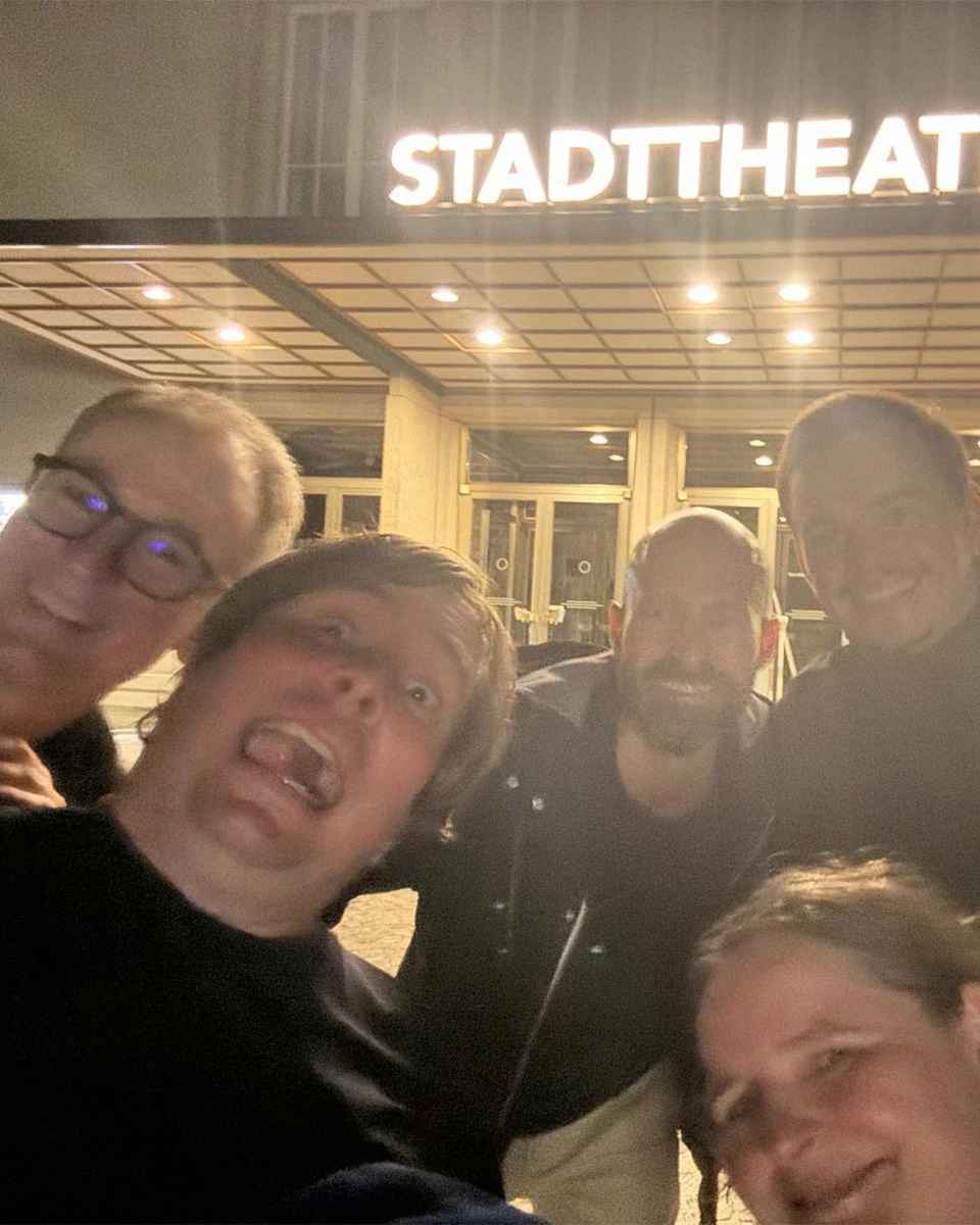 Nächtliches Gruppenselfie von fünf Personen mit Grimassen vor dem beleuchteten Eingang mit dem Schriftzug «Stadttheater»