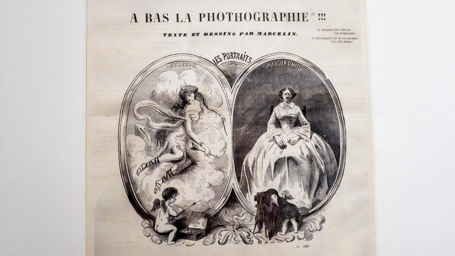 Historische Karikatur «A bas la Photographie!!!» von Marcelin: links eine gezeichnete Muse in Wolken, rechts eine steif sitzende Frau vor einer Fotokamera.